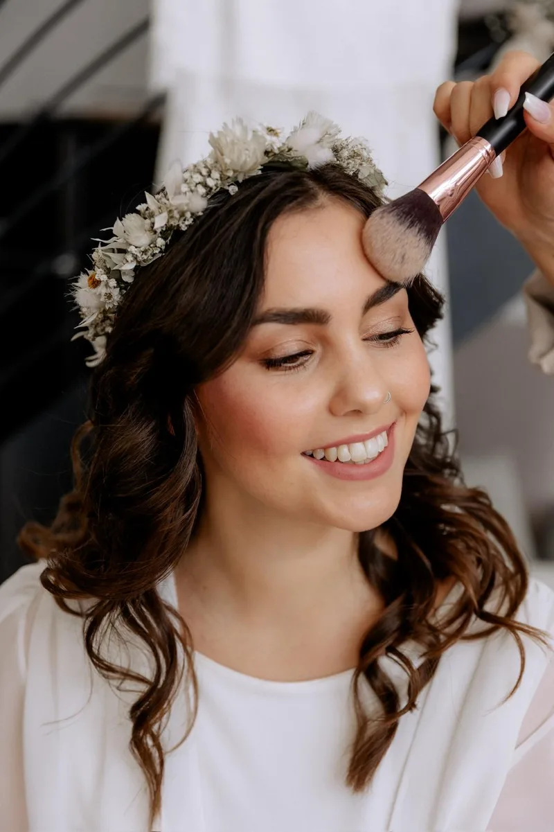 Braut mit Blumenkranz beim Make-up, Rouge wird aufgetragen – DK Beauty Lounge Bodelshausen