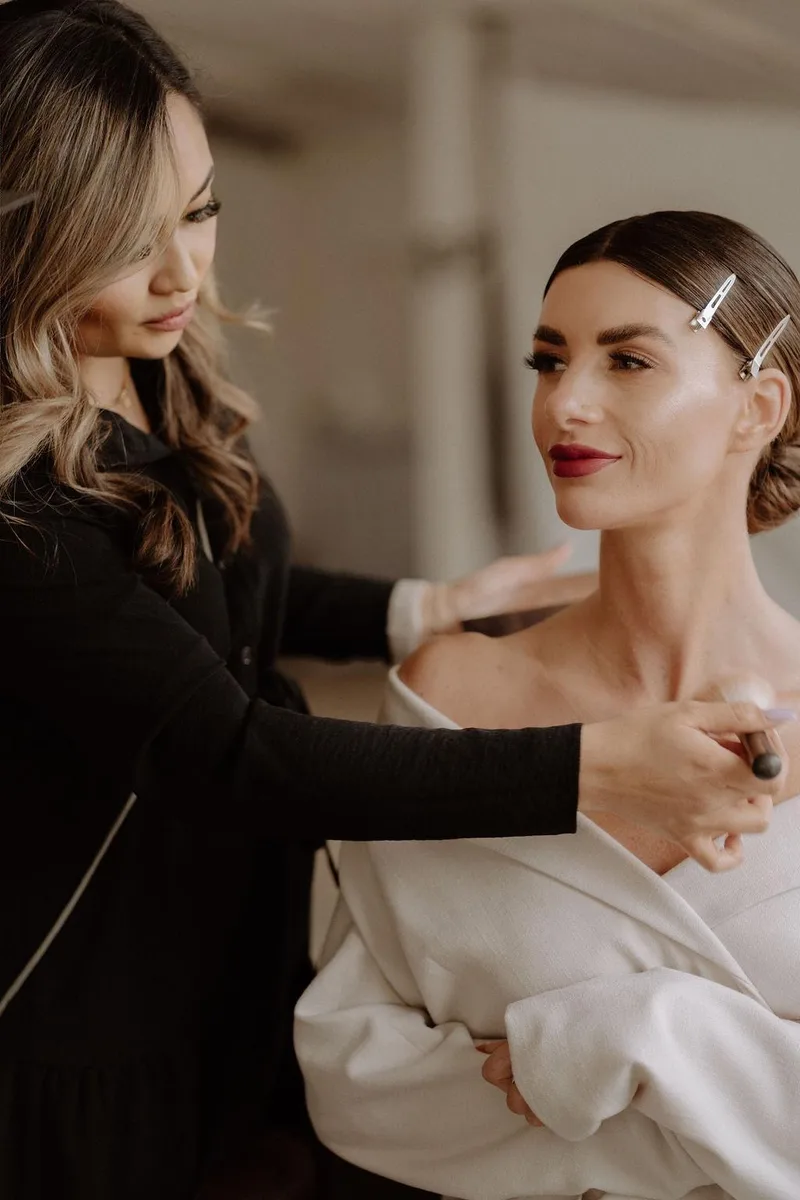 Braut mit Hochsteckfrisur und rotem Lippenstift beim letzten Feinschliff – DK Beauty Lounge Bodelshausen