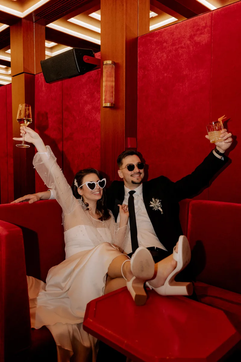 Paar mit Sonnenbrillen und Sektgläsern in roter Loungebestuhlung – Styling von Dilya Klein – DK Beauty Lounge Bodelshausen