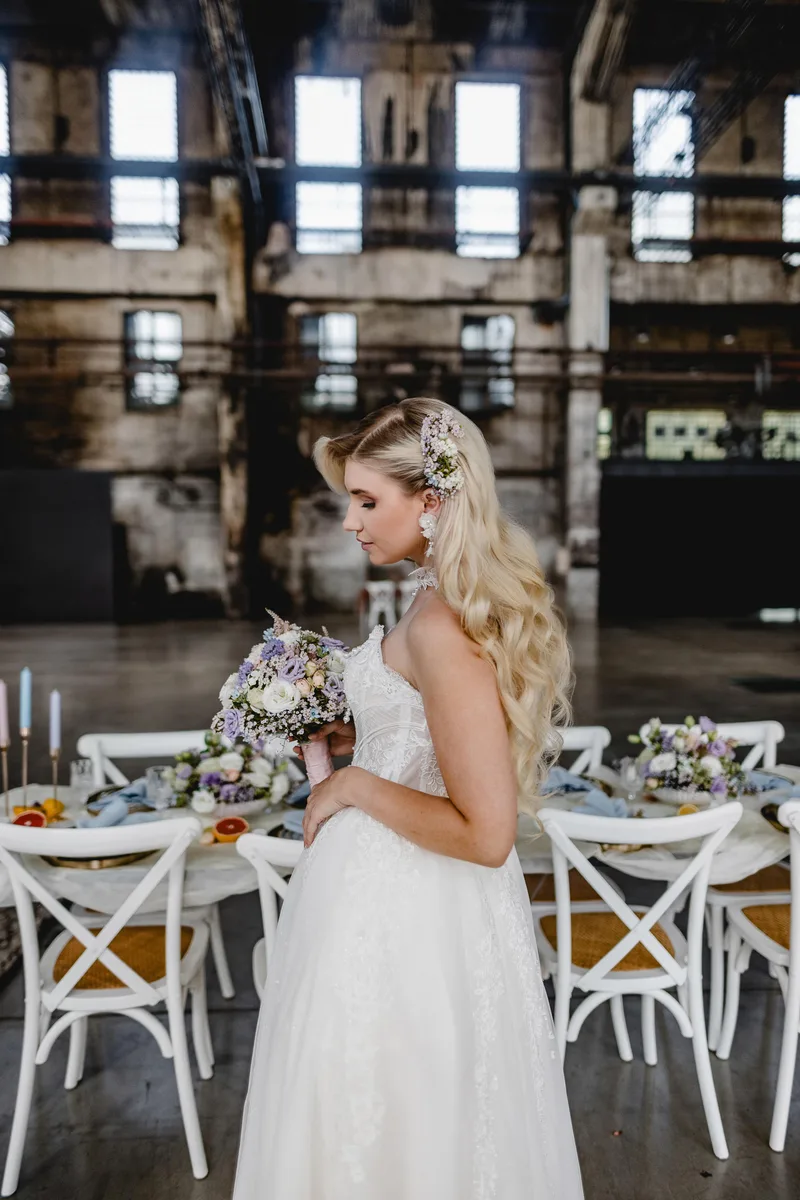 Modell mit langen blonden Wellen und Blumenschmuck im Haar in einer Industriehalle – Styling von Dilya Klein – DK Beauty Lounge Bodelshausen